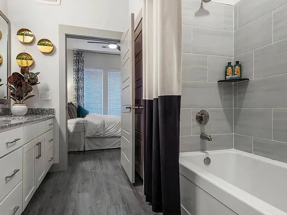 Tub and Vanity Bathroom With Granite Countertops and Bedroom Access