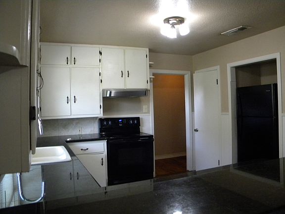 Kitchen with black appliances and granite counter tops.
