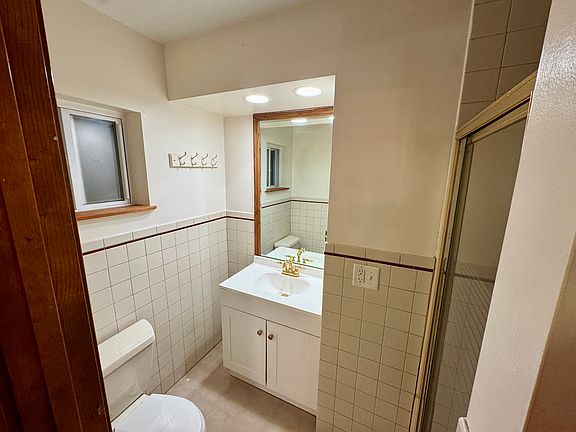 Efficient bathroom with standing shower and gold finishes.