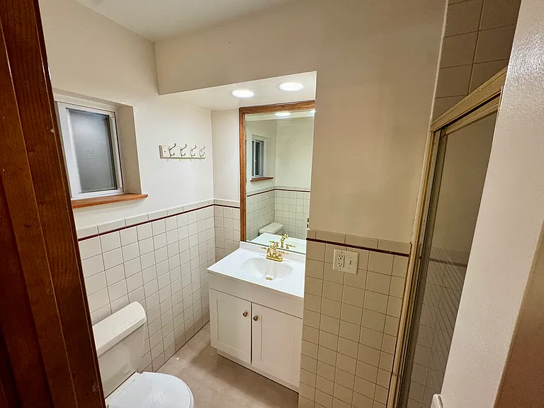 Efficient bath with standing shower and gold fixtures.