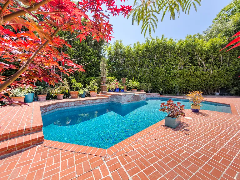 Vibrant Japanese maple frames this pool with a cascading water feature at this Beverly Hills luxury rental, 1094 Garden Lane, 90210.