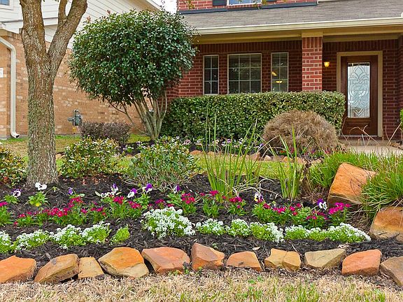 Stone-lined flower beds highlight the professional landscaping which graces the front entrance of th
