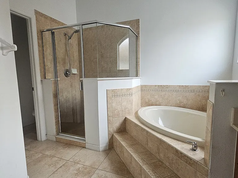 Large master suite bathroom with shower, huge tub, tons of natural sunlight, double sinks, walk in closet with shoe rack, separate additional closet space, and separate room for toilet.