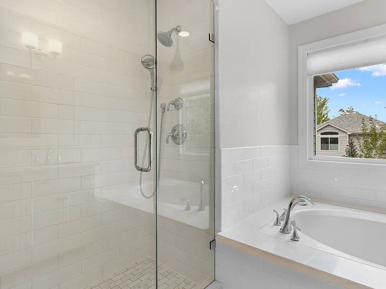 The walk-in shower features classic subway tile detailing and a built-in bench for added comfort and functionality.