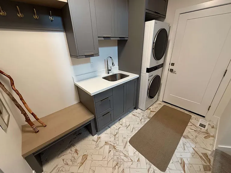 Mudroom with stacked washer and dryer, sink and ample storage
Garage enterance