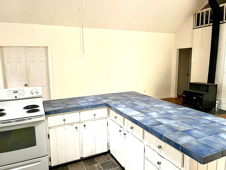 Kitchen counter, entrance to living room on the left, and bathroom and bedrooms on the right.