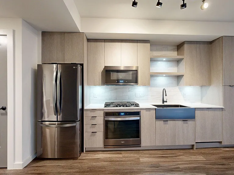 Apartment Kitchen with Stainless Steel Appliances, Quartz counter tops and Wood Style Flooring.