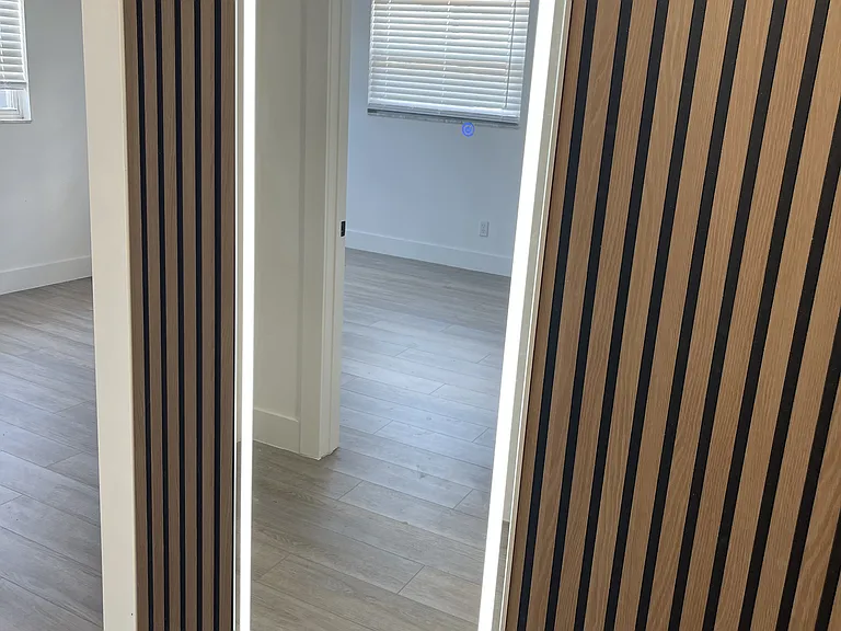 modern mirrors with ligh over wood panels.