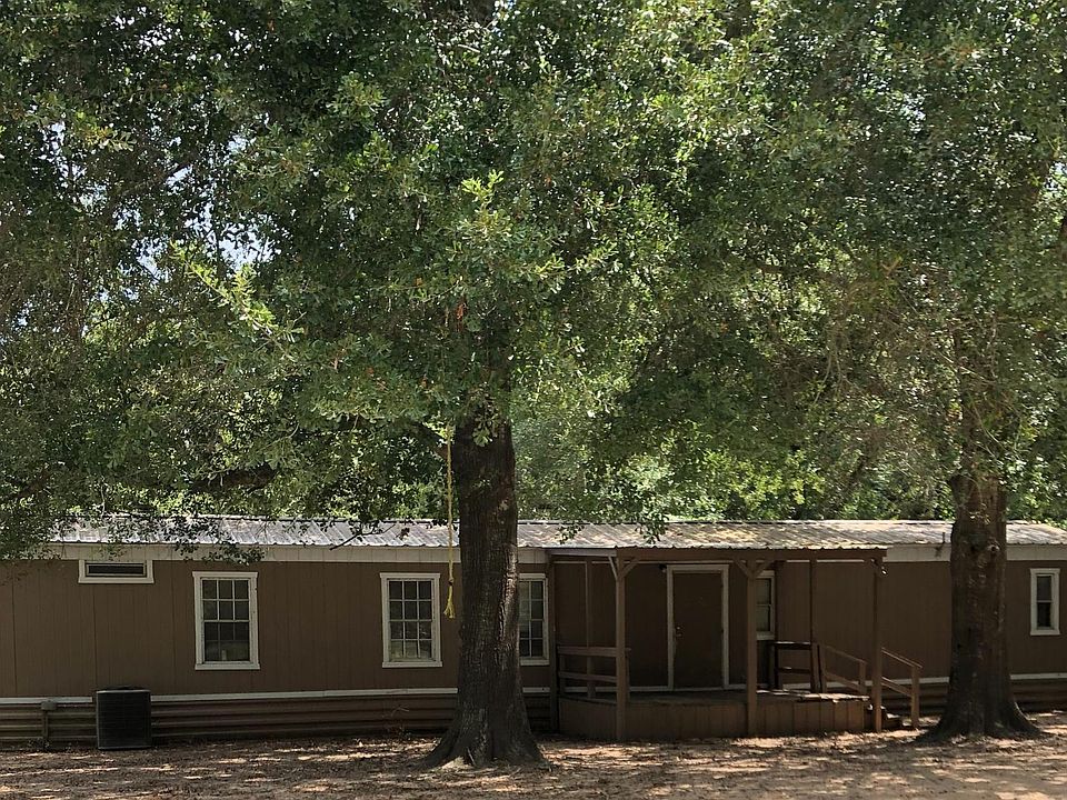 Large shade trees surround front of home. Mobile home sits off road to offer a private setting.