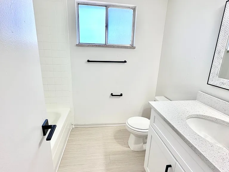 Bright, modern bathroom with sleek white cabinetry, elegant fixtures, and abundant natural light.