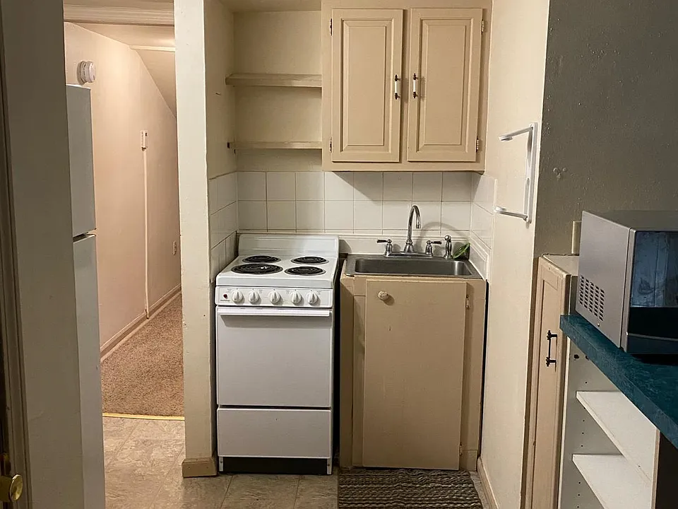Full kitchen with refrigerator, range, sink, cabinetry and additional open storage. BEFORE renovation _ new LVP flooring will continue through this area