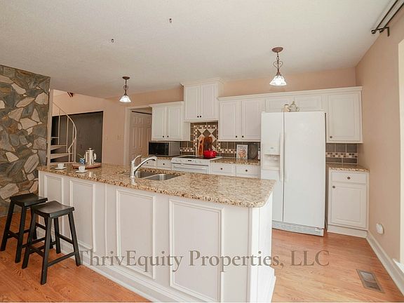 Large center island, bar seating, and spiral staircase leading to upstairs loft.