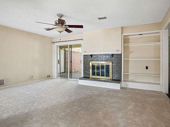 Den with fireplace with gas starter and glass fireplace doors, with built-in bookshelves to the right side.