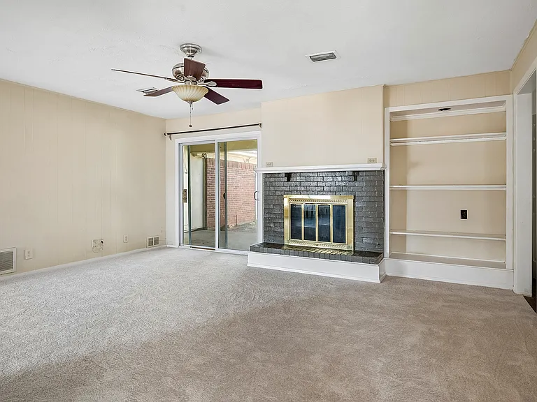 Den with fireplace with gas starter and glass fireplace doors, with built-in bookshelves to the right side.