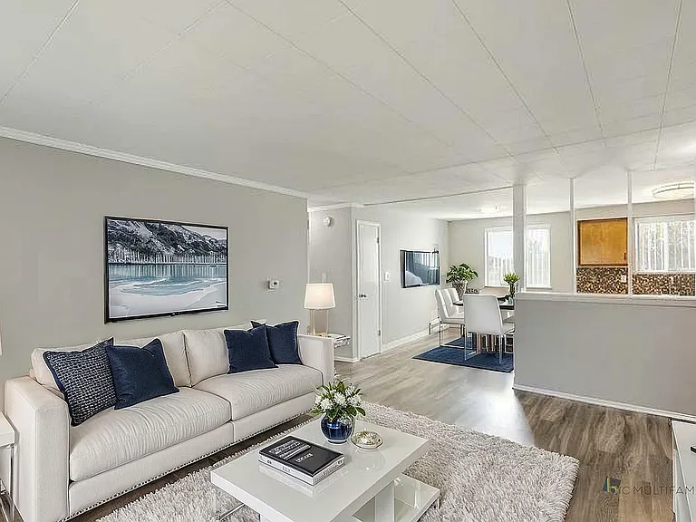 Chic modern living room with plush white sofa, elegant decor, and open-plan dining area in a bright, inviting atmosphere.