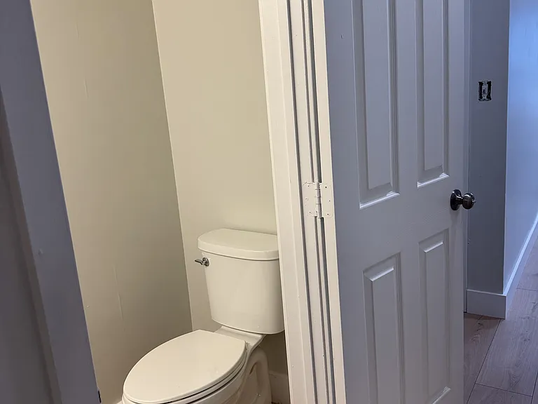 Fully renovated powder room with a stylish mirror and ribbed light bar (2/2).