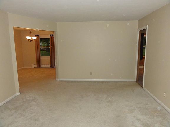 View of the Living room from the large picture window. Also pictured: dining room, and doorway to the family room (to the right).