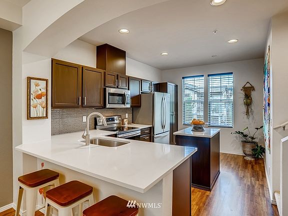 Updated kitchen with quartz countertops, tile backsplash, countertop depth SS fridge and pantry storage