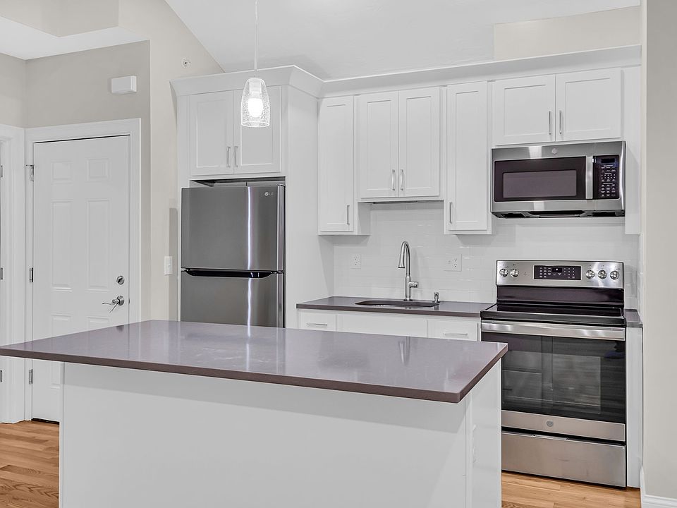 Kitchen with stainless steel refrigerator, electric range and microwave with view of 2nd entry door.