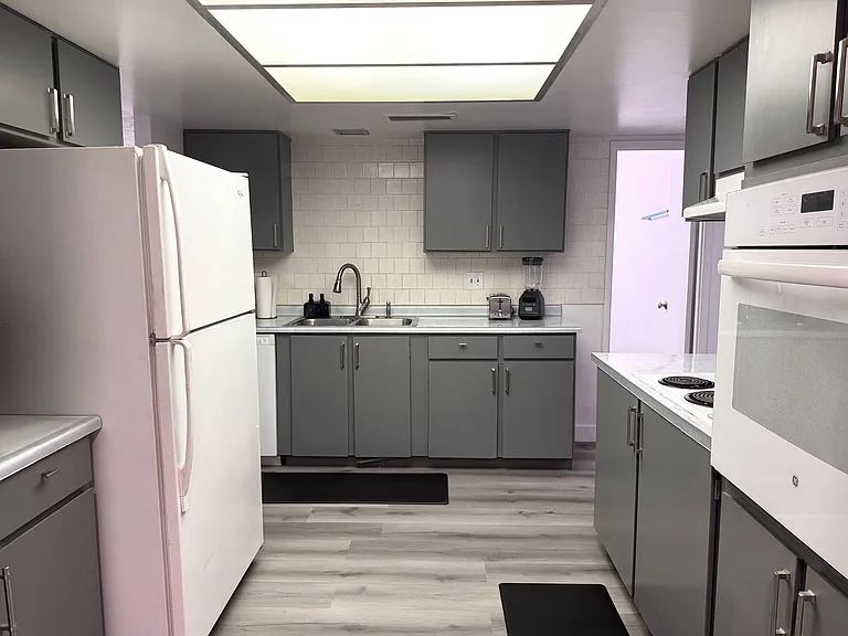 Efficient kitchen with ample cabinetry, subway-tile backsplash, double sink, and full appliance package for easy meal prep.