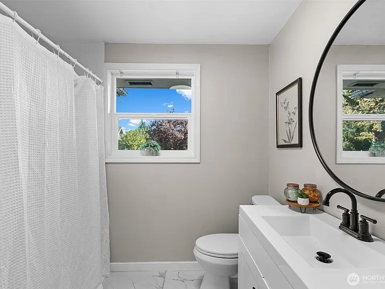 Bathroom with a tub/shower combo, large vanity, and a window for fresh air and natural light.