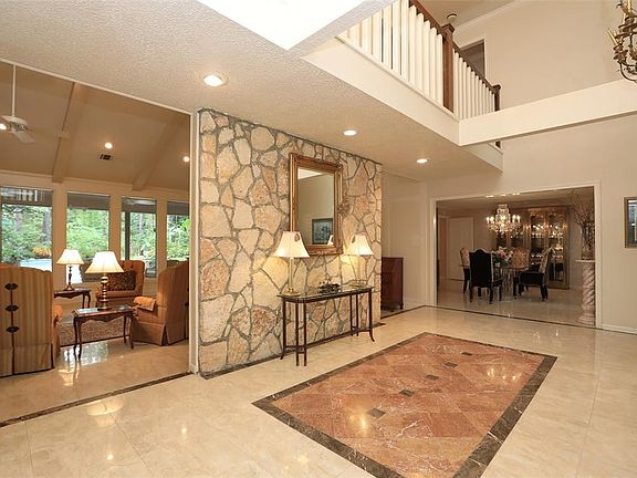 The elegant foyer has a soaring ceiling, a rock accent wall and imported Italian porcelain tile with marble insets that carry throughout the first floor.