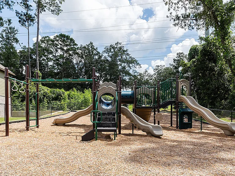 Inviting outdoor playground with slides and climbing structures, nestled in a lush green setting perfect for fun.