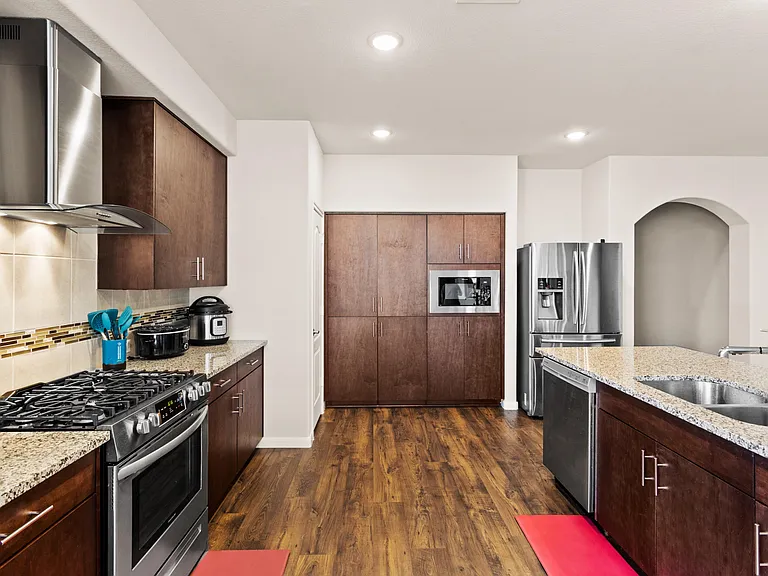 Spacious kitchen with granite countertops, ample cabinetry, gas range, built-in microwave, and stainless fridge plus dishwash