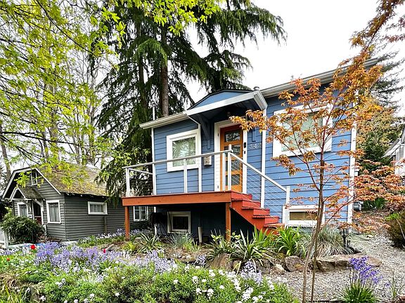 Street view of home and front yard with flower beds and Japanese maple tree