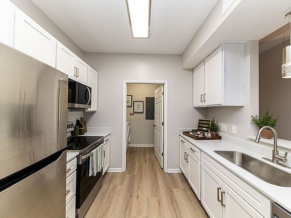 Kitchen with quartz counters, modern cabinetry, & hardwood-style flooring