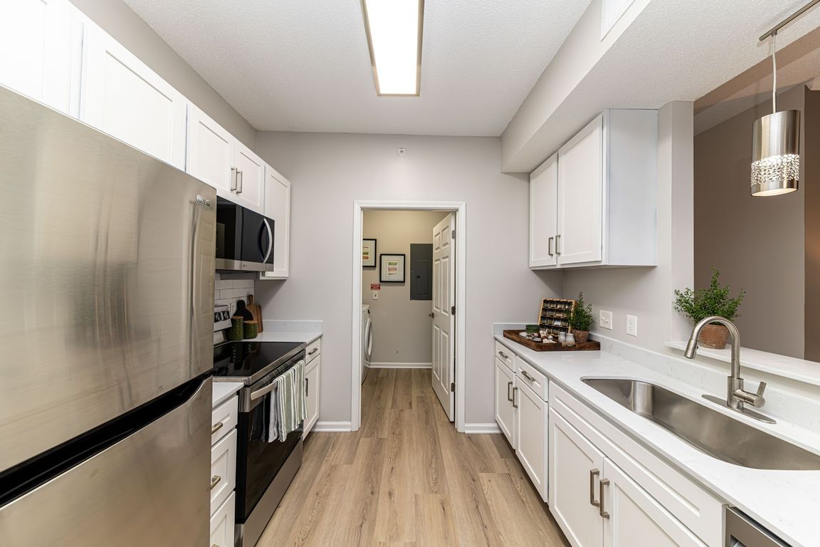 Kitchen with quartz counters, modern cabinetry, & hardwood-style flooring