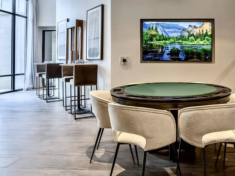 Clubhouse Game Room Featuring Round Poker Table and Upholstered Chairs