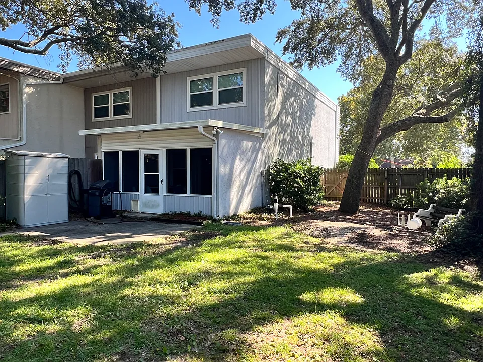 Shaded, fenced back yard, showing screened porch and patio area.