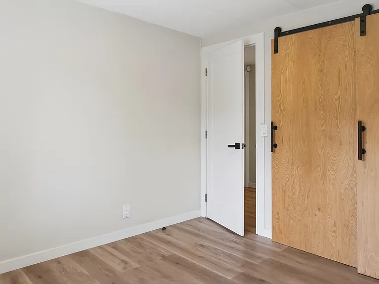 Second Bedroom with Sliding Barn Door Closet and Hardwood-Style Flooring