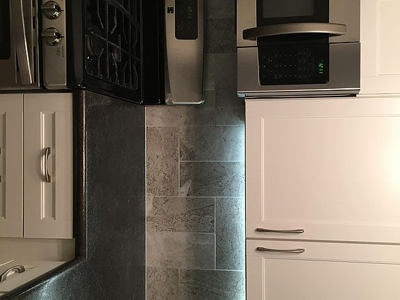 Kitchen- white cupboards with stainless appliances. Dishwasher, refrigerator, oven and microwave.