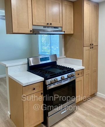 Kitchen view of 30 inch gas range with mechanical range hood.