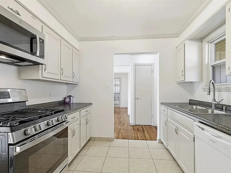 Galley kitchen with refrigerator, stove, microwave, dishwasher, and plenty of cabinet storage.