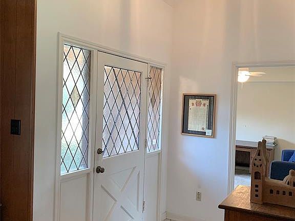 Inviting tiled entry with high ceilings and pretty leaded glass front door with side panels.