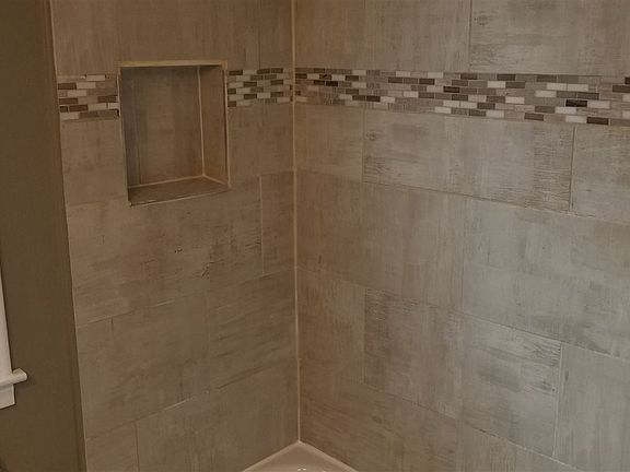 Ceramic tub surround with mosaic tile inlays.