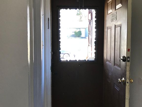 View going out front door. Kitchen on R. Bathroom on L.