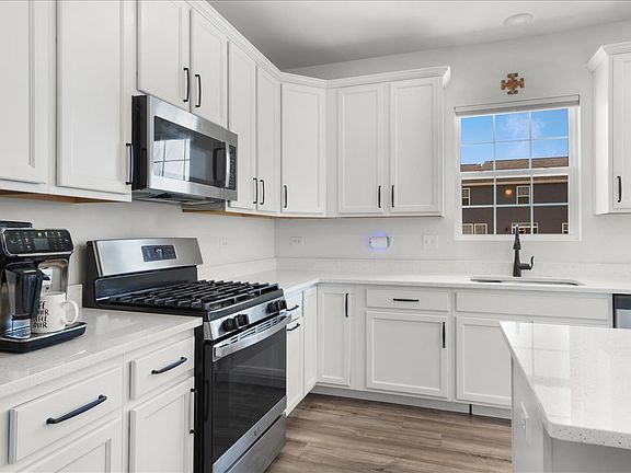 Executive kitchen with all white cabinets, granite counters, and island with bar seating.
