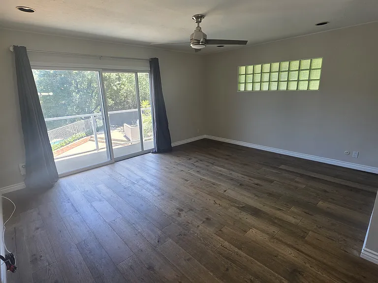 Master bedroom on second floor overlooking pool with slider out to glass balcony overlooking pool and to the right the backyard