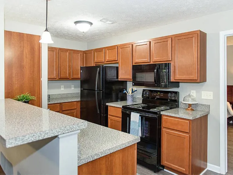 Well-equipped kitchen with black appliances, plenty of cupboard space, and brown cabinetry