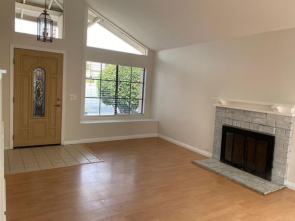 Brightly lit living room with vaulted ceilings and fireplace