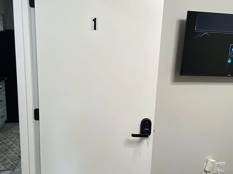 Private, keyed interior room entry with sleek hardware and nearby wall-mounted TV for added convenience.