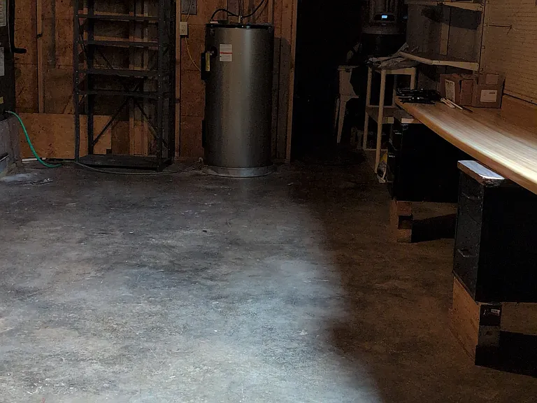 basement mechanical room with concrete floor and door to outside.