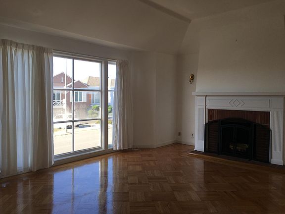 living room features hardwood floors, high ceiling, large windows and fireplace