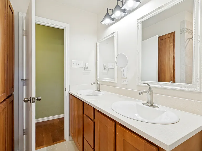 An updated full bath is just steps away from the secondary bedrooms, offers an updated tub/shower combo with large-tiled flooring, tasteful nickel finishings, dual sinks in a taller vanity with drawers, and extra linen storage behind the door.