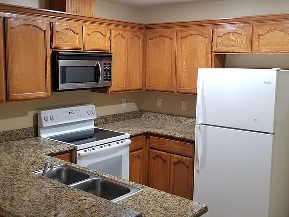 Kitchen with appliances: microwave, refrigerator and flat-top stove.