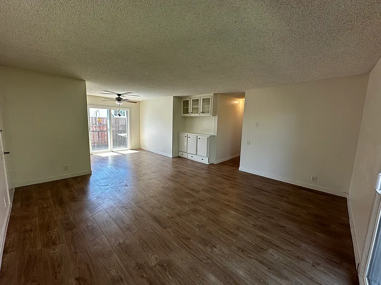 Wider view of Living Room with view of access to Large Patio to the right, hallway access to the Bedrooms and Bathrooms in the center